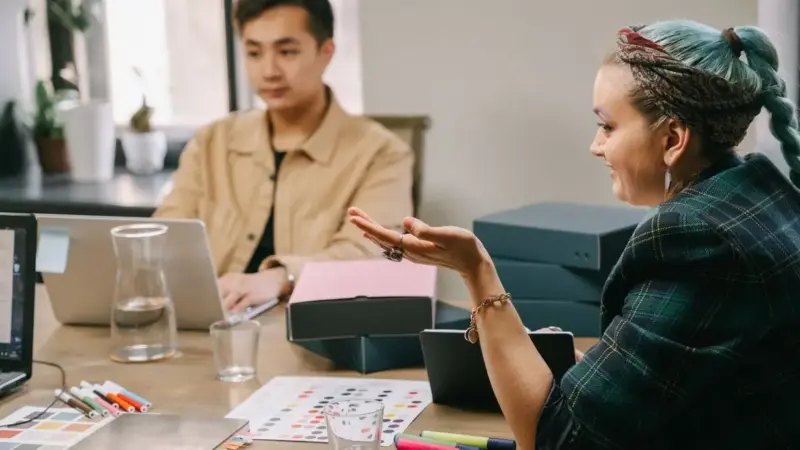 Two coworkers engaged in a productive strategy meeting at a modern office desk.